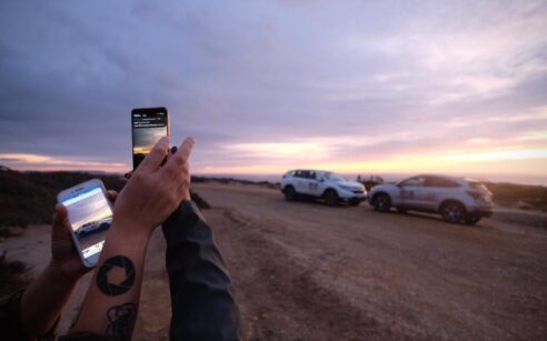 Duas mãos com telemóveis a fotografar CR-V e HR-V na Estrada Nacional 2
