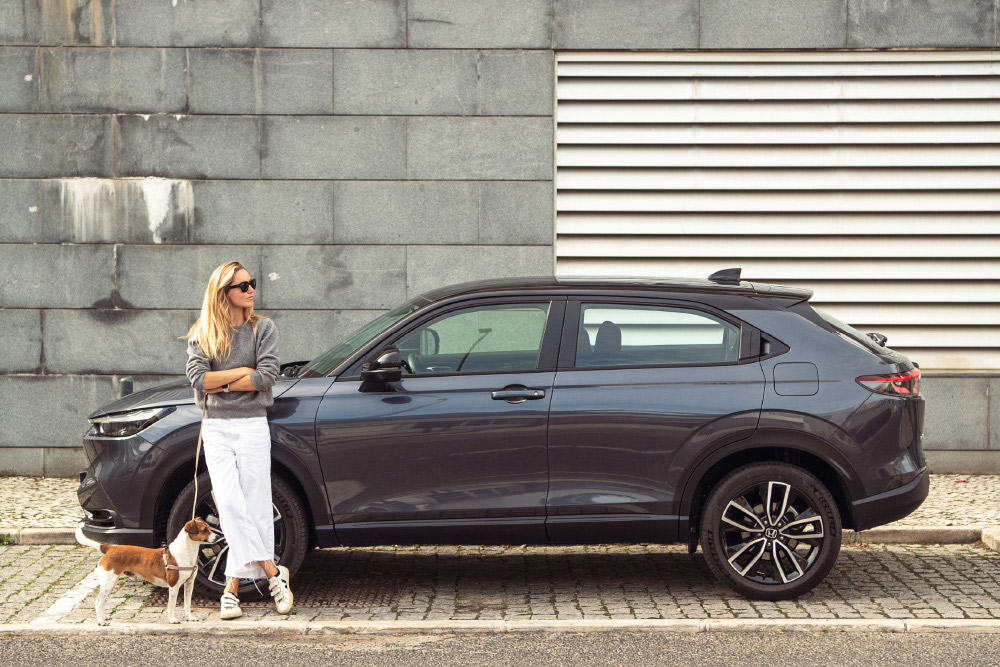 Mulher com um cão encostada a um Honda