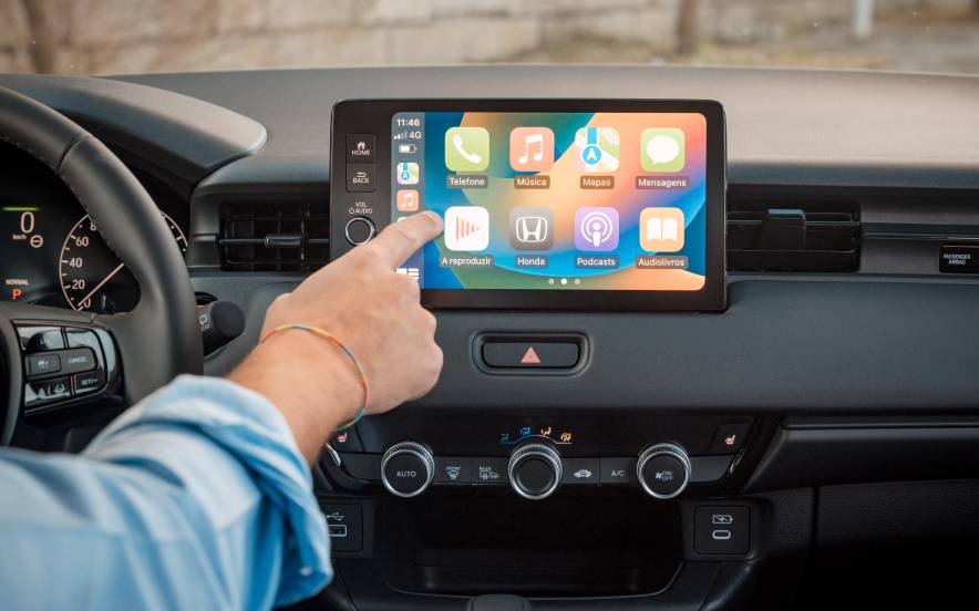 Interior do Honda HR-V híbrido com um condutor a interagir com o ecrã tátil, evidenciando o seu conforto e tecnologia.