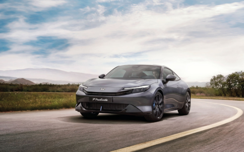 Honda Prelude 2026, na cor Meteoroid Grey Metallic, a circular em estrada aberta com uma paisagem natural, destacando o seu design moderno.