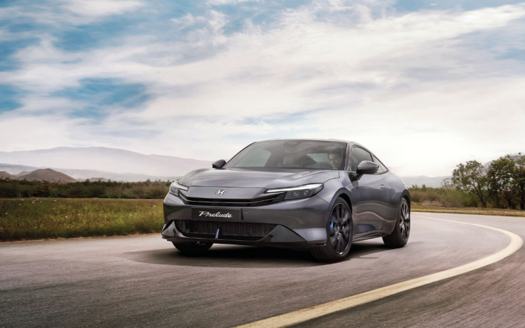 Honda Prelude 2026, na cor Meteoroid Grey Metallic, a circular em estrada aberta com uma paisagem natural, destacando o seu design moderno.