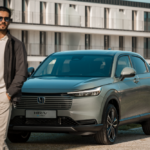 Honda HR-V híbrido estacionado junto ao mar e em frente a um edifício moderno, com o condutor a caminhar ao lado.