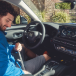 Homem a apertar o cinto de segurança enquanto está sentado no lugar do condutor de um automóvel Honda